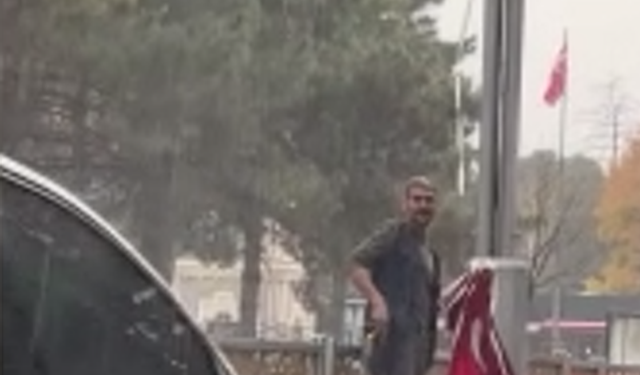 Yağan yağmura aldırmadan düşen bayrakları topladı